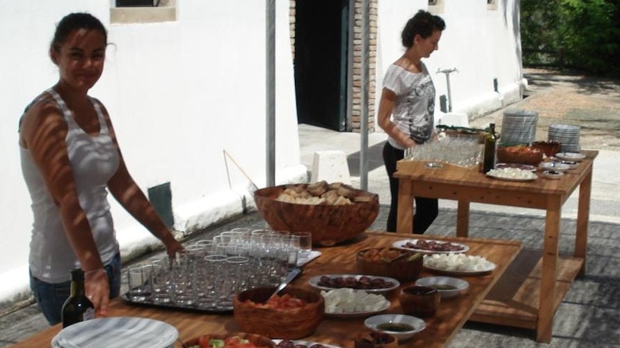 two girls waiting to welcome the tourists with aperitifs, wine on the tables at 'Theotoky Estate' outside